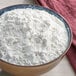 A bowl of Bob's Red Mill unbleached artisan bread flour on a table.