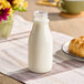 A Captiva Containers clear juice bottle filled with milk on a table.