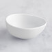 A white irregular round melamine ramekin on a white surface.