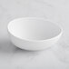 A white GET Enterprises Riverstone melamine bowl on a marble surface.