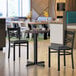 A 30-inch round reversible table with a white birch and ash laminated top, shown with two black chairs in a modern dining setting.