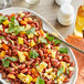 A plate of Goya red kidney beans and corn salad on a table with a stack of white plates.