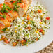 A plate of Goya parboiled rice with chicken and vegetables on a wicker mat.