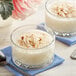 A glass bowl filled with cream of coconut dessert topped with shredded coconut.