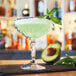 An Arcoroc coupe glass filled with a drink and garnished with an avocado slice and mint leaves.