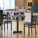 A Lancaster Table & Seating white and gray slate laminated table top on a black table with black chairs.