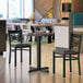 A Lancaster Table & Seating white birch and ash laminated table top on a black metal table in a restaurant.