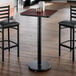 A square, reversible cherry and black laminated table top on a single pedestal base, set in a restaurant environment.