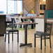 A Lancaster Table & Seating square table top with a reversible walnut and oak design on a table in a restaurant.