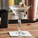A close up of an Arcoroc martini glass with a green olive in it.