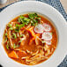 A bowl of soup with chicken, radishes, and carrots with Maggi Jugo seasoning sauce.