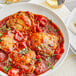 A white bowl of food with Goya Spanish-Style Tomato Sauce and a fork and knife.