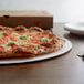 A 16" white pizza on a corrugated circle on a table in a pizza parlor.