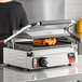 A woman using a Vollrath Cayenne Panini Sandwich Press to grill a sandwich.