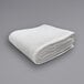 A folded white Oxford Jaipur thermal honeycomb hotel blanket on a gray surface.