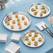 A group of silver Acopa stainless steel platters with food on them.