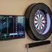 An Arachnid Prodigy dart board mounted on a wall next to a TV.