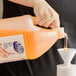 A hand pouring Dial hair and body wash into a plastic bottle.