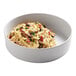 A stackable white melamine bowl filled with pasta, olives, and peppers.
