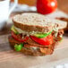 A sandwich with Upton's Naturals seitan bacon strips, tomatoes, and avocado on a cutting board.