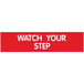 A red rectangular sign with white text that says "Watch Your Step"