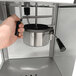 A hand holding a metal bowl of popcorn popped in a Paragon Mod Pop Popcorn Machine.