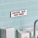 A white and red Cosco "Employees Must Wash Hands" sign on a wall.