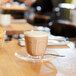 An Arcoroc glass cup of coffee on a saucer.