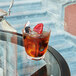 A Arcoroc old fashioned glass of iced tea with fruit on a table.