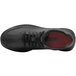 A black leather Shoes For Crews women's athletic shoe with a red sole on a table.