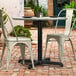 A black table base with a white chair and table on a brick patio.