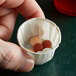 A hand holding a Genpak Harvest paper souffle cup filled with pills.