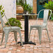 A black Lancaster Table & Seating table base on a brick patio with two chairs.