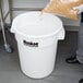 A man pouring rice into a white Continental Huskee ingredient storage bin with a flat top lid.