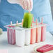 A person putting a pink Fox Run ice pop in a tray with green, pink, and white Fox Run ice pops.