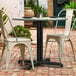 A white chair and table on a brick patio with a black table base.