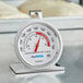 An AvaTemp hot holding thermometer with a red and white dial on a metal surface.