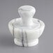 A white marble mortar and pestle set by Fox Run on a counter.
