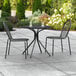 A Lancaster Table & Seating Harbor black table with chairs on a patio.