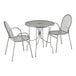 A Lancaster Table & Seating Harbor Gray round outdoor table with ornate legs and two arm chairs.