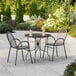 A Lancaster Table & Seating Harbor black round table with two arm chairs on an outdoor patio.