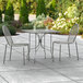 A Lancaster Table & Seating Harbor Gray outdoor table with two chairs on a patio.