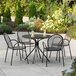 A Lancaster Table & Seating Harbor black outdoor table with chairs on a patio.