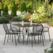 A Lancaster Table & Seating Harbor Black table with ornate legs and 4 arm chairs on a patio.