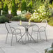 A Lancaster Table & Seating Harbor Gray table and chairs on an outdoor patio with two cups on the table.