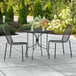 A Lancaster Table & Seating rectangular black outdoor table with two chairs on a patio.