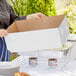 A woman setting up a Choice Disposable White Chafer Wind Guard on a table outdoors.