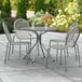 A Lancaster Table & Seating Harbor Gray outdoor table and chairs on a patio.