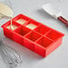 A red Choice silicone ice mold being filled with a white substance.