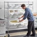 A man putting food into white Baker's Lane containers on a shelf.